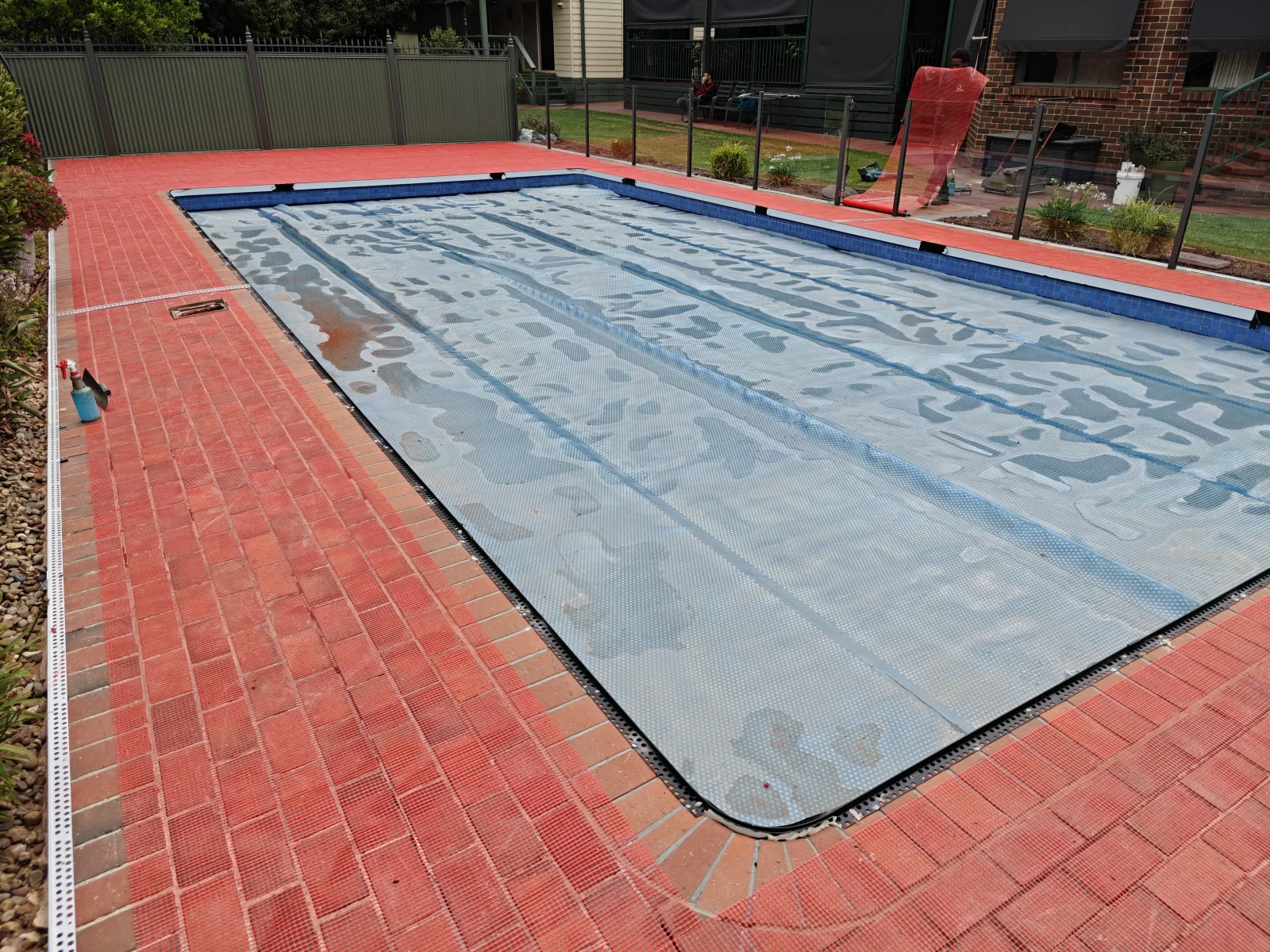 Existing red pavers around a swimming pool before resurfacing