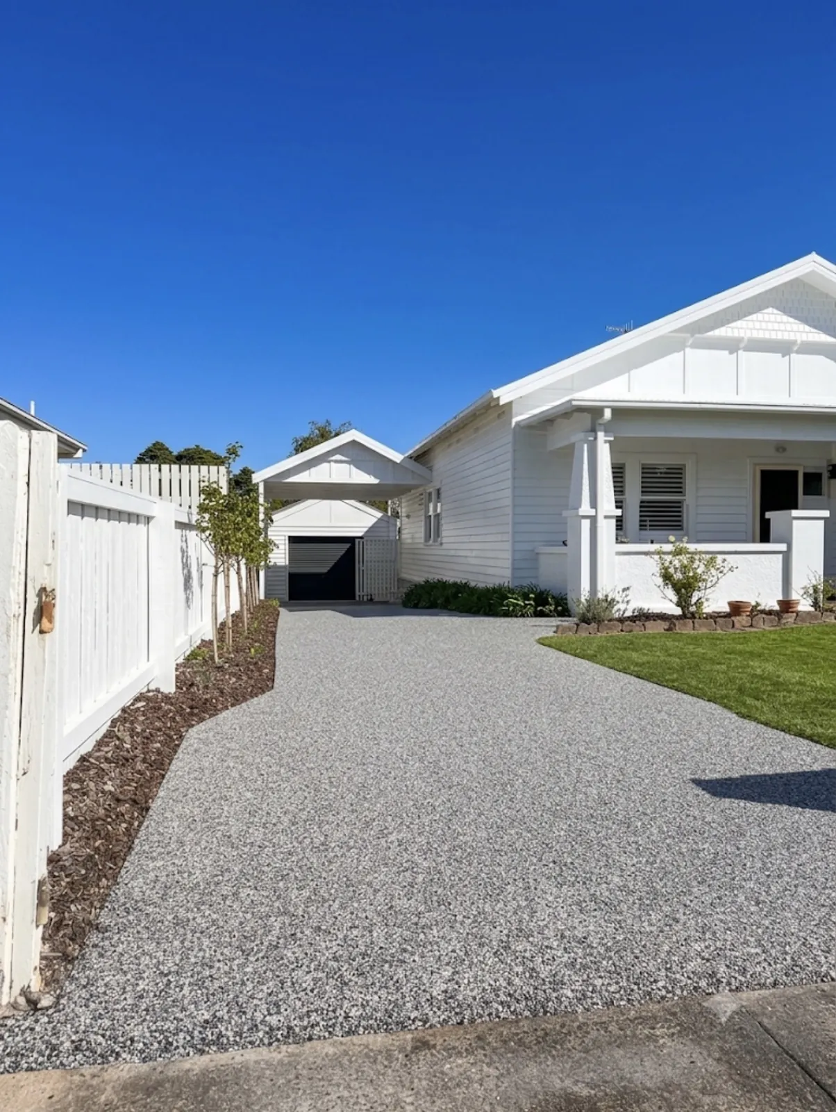 Light grey resin-bound stone driveway at a white weatherboard home