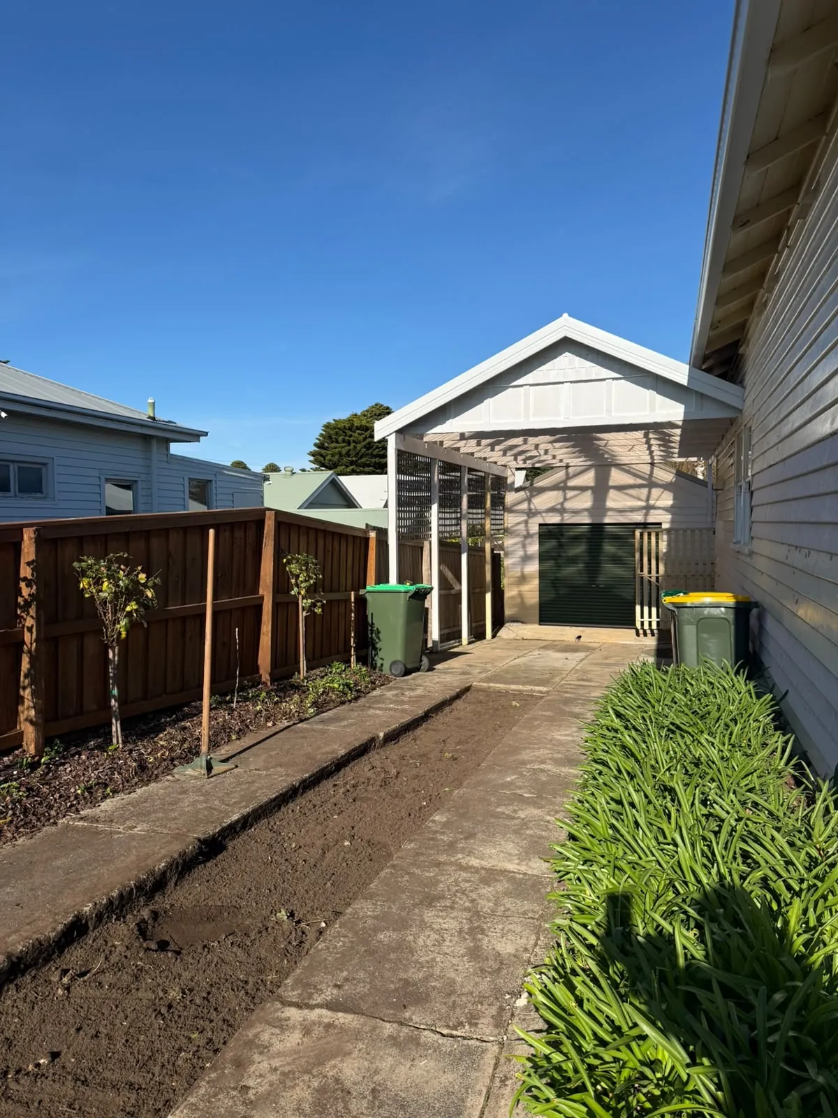 Worn concrete side path alongside a weatherboard house, before resurfacing
