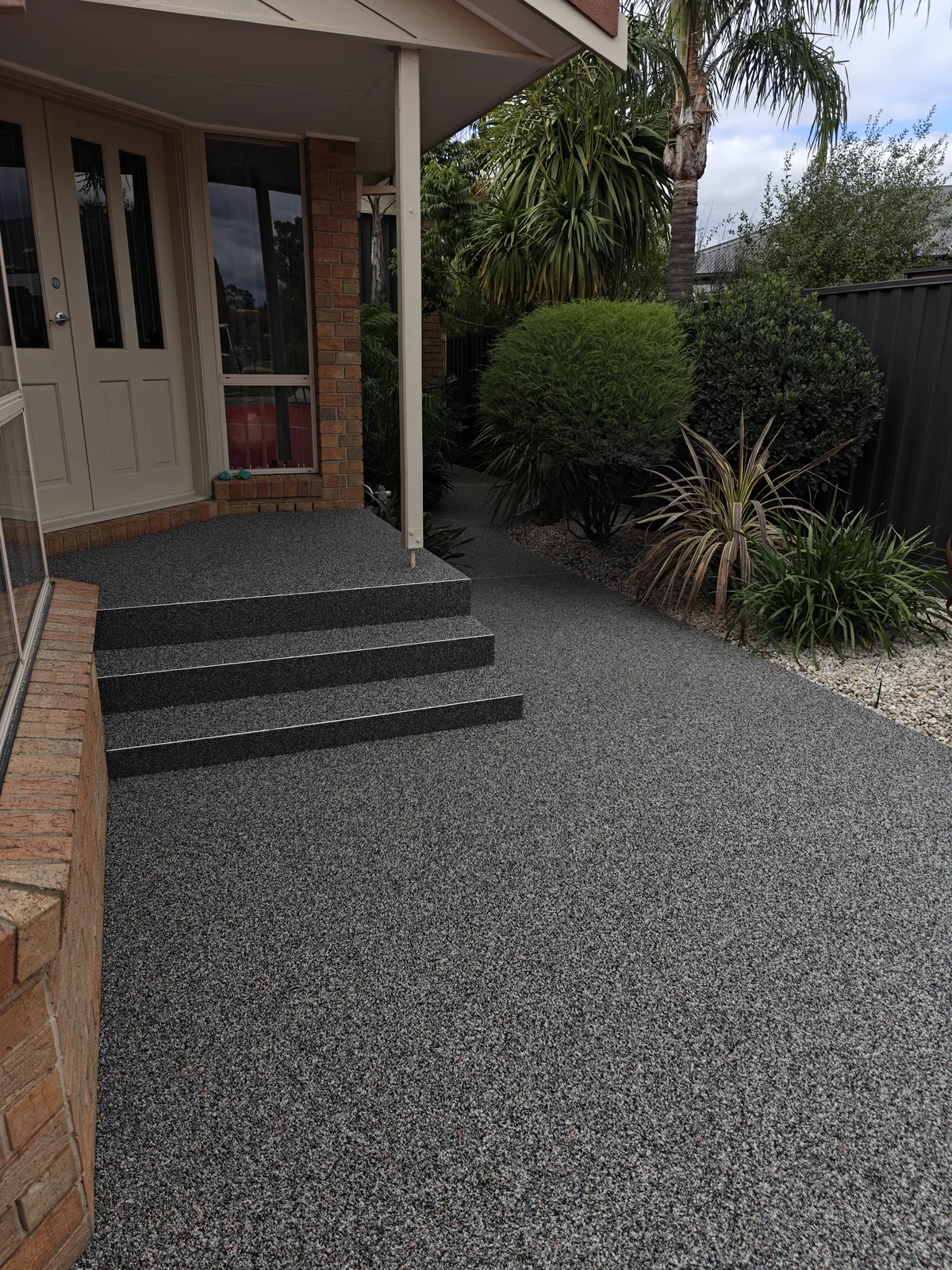 Front entry with four Carbon Black stone steps and path alongside brick house