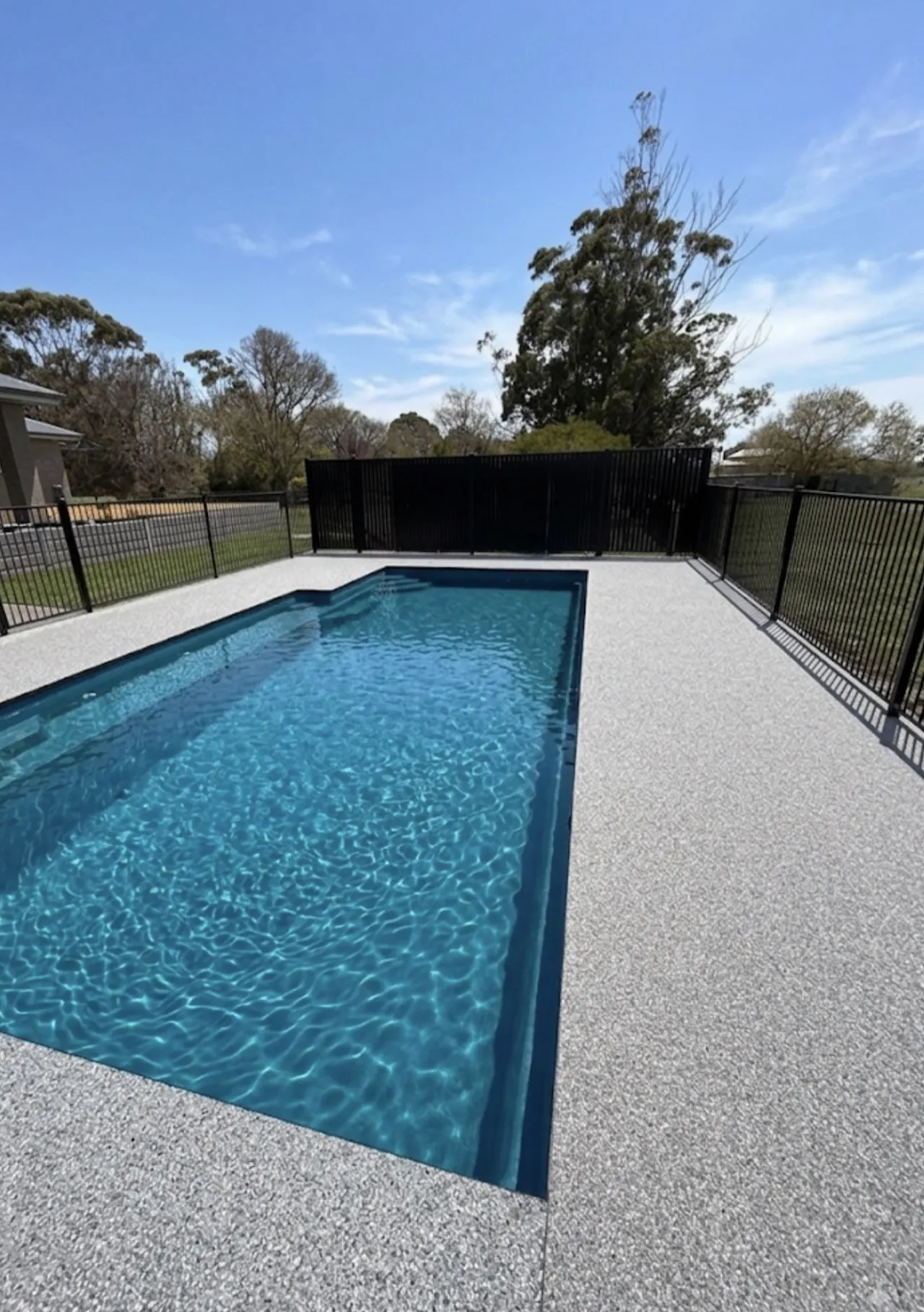 Pool surround in light grey Bluestone blend, blue sky, black metal fence