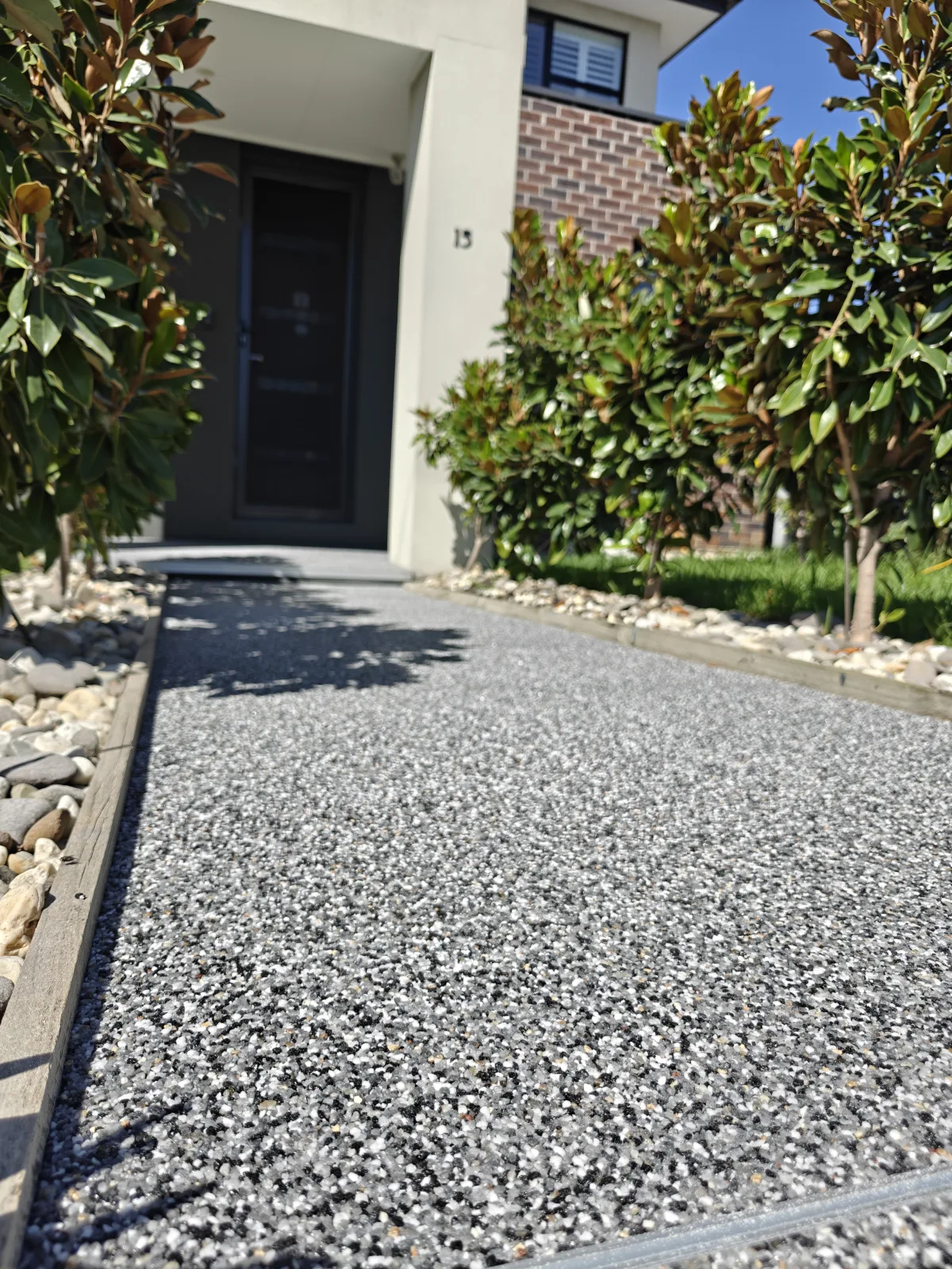 Dark resin-bound stone front path framed by planting