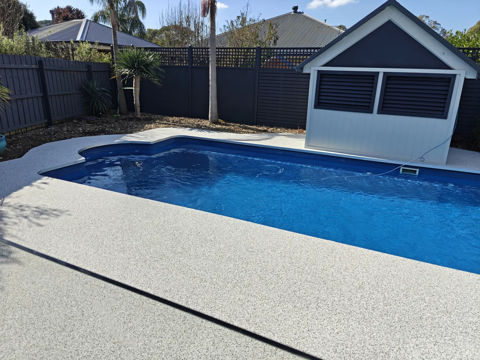 Light resin-bound stone around a blue swimming pool